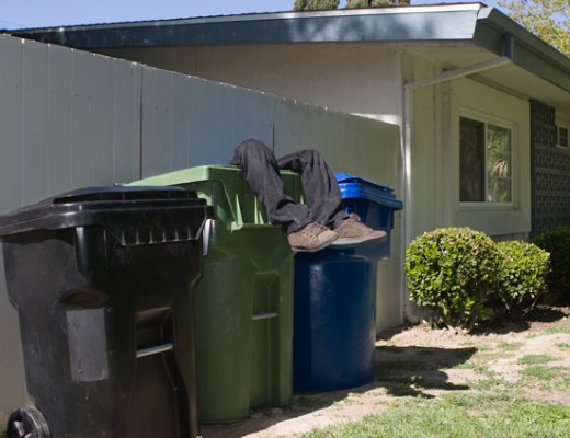 Man's legs extending from garbage can