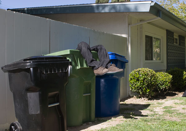 Man's legs extending from garbage can